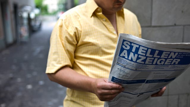 Mann in gelbem Hemd liest den Stellenanzeiger. Mann in gelbem Hemd liest den Stellenanzeiger.