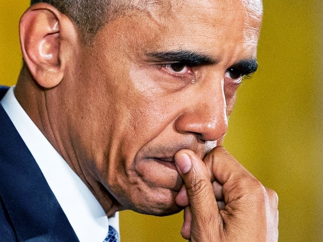Barack Obama verzieht seinen Mund und hält die Hand davor.