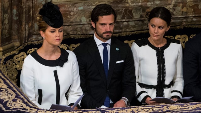Prinzessin Madeleine und Prinzessin Sofia sitzen in einem ähnlichen schwarz-weissen Kleid im Parlament von Schweden. Dazwischen ist Prinz Carl Philipp. Prinzessin Madeleine und Prinzessin Sofia sitzen in einem ähnlichen schwarz-weissen Kleid im Parlament von Schweden. Dazwischen ist Prinz Carl Philipp.
