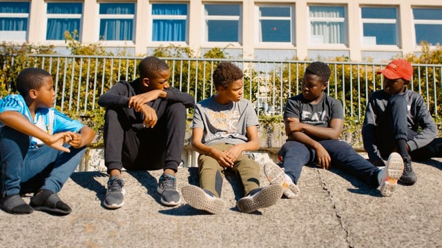 Fünf Jungs sitzen draussen auf dem Boden. Fünf Jungs sitzen draussen auf dem Boden.