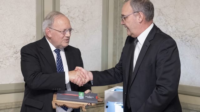 Parmelin verabschiedet Schneider-Ammann mit einem Händedruck. Parmelin verabschiedet Schneider-Ammann mit einem Händedruck.