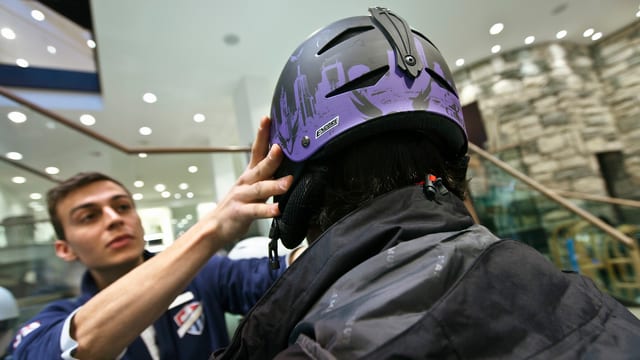 Einem Mann wird in einem Wintersportgeschäft ein Ski-Helm aufgesetzt. Einem Mann wird in einem Wintersportgeschäft ein Ski-Helm aufgesetzt.