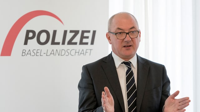 Isaac Reber steht vor einem Logo der Baselbieter Polizei Isaac Reber steht vor einem Logo der Baselbieter Polizei