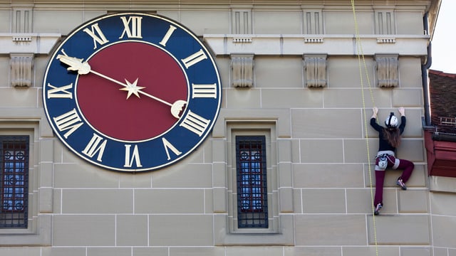 Frau klettert an Turm mit Uhr Frau klettert an Turm mit Uhr