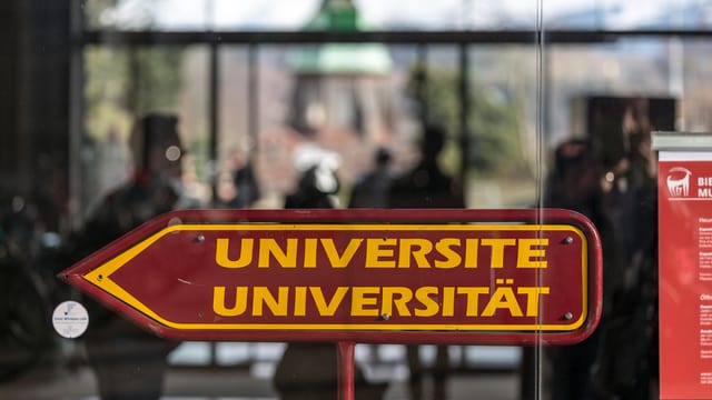 Ein Pfeil, zweisprachig angeschrieben, weist den Weg zur Universität. Ein Pfeil, zweisprachig angeschrieben, weist den Weg zur Universität.