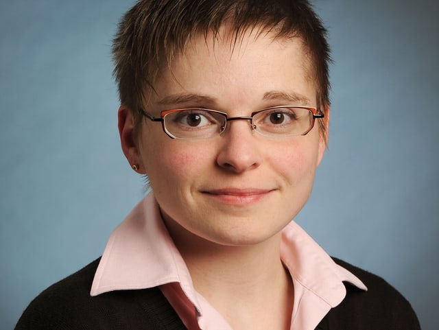 Porträt von Claudia Hänzi vor dunklem Hintergrund. Porträt von Claudia Hänzi vor dunklem Hintergrund.
