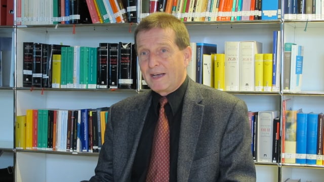 Mann sitzt vor Bücherwand. Mann sitzt vor Bücherwand.
