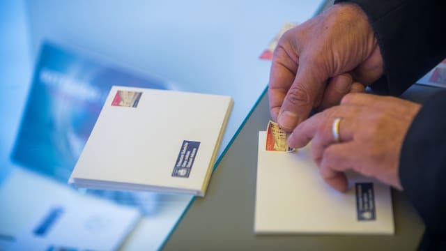 Hände kleben Marke auf Couvert. Hände kleben Marke auf Couvert.