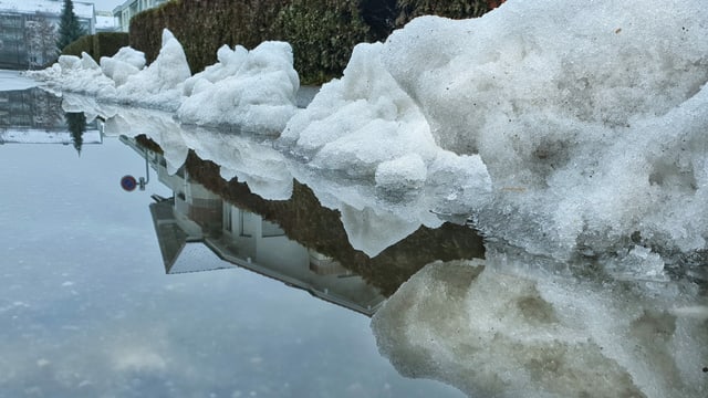 Schneereste und gestautes Wasser auf Strasse. Schneereste und gestautes Wasser auf Strasse.