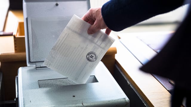 Wählerin legt Wahlzettel in die Urne Wählerin legt Wahlzettel in die Urne