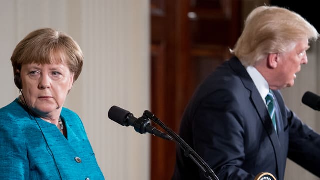 Merkel und Trump stehen nebeneinander. Beide schauen in die jeweils andere Richtung. Merkel und Trump stehen nebeneinander. Beide schauen in die jeweils andere Richtung.