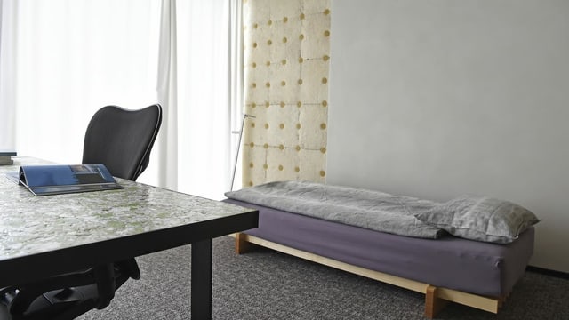 Schlicht eingerichtetes Zimmer mit einem Bett, Bürotisch und -Stuhl. Schlicht eingerichtetes Zimmer mit einem Bett, Bürotisch und -Stuhl.