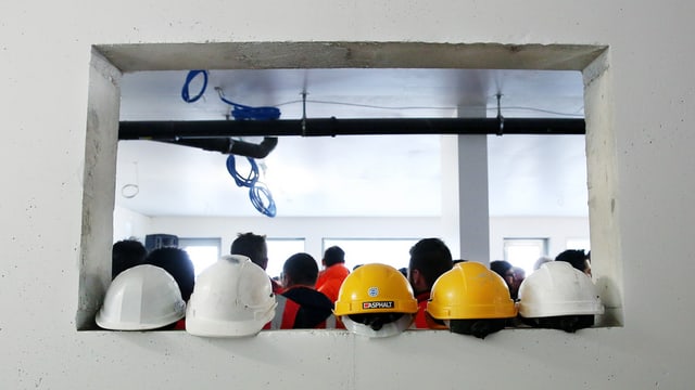 Fünf Bauhelme auf einer Mauer Fünf Bauhelme auf einer Mauer