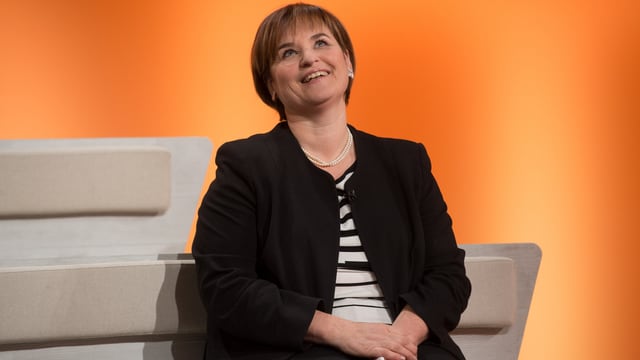Marina Carobbio sitzt vor orangem Hintergrund, sie lacht. Marina Carobbio sitzt vor orangem Hintergrund, sie lacht.