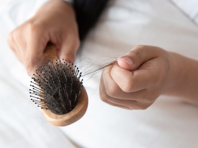 Jemand zieht Haare aus einer Bürste. Jemand zieht Haare aus einer Bürste.
