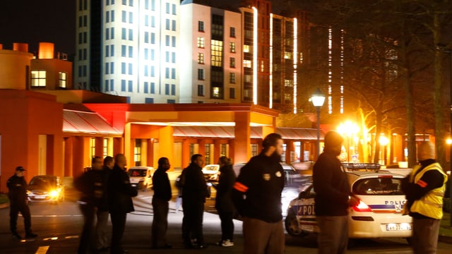 Polizeiautos und Polizisten vor einem hellerleuchteten Gebäude. Polizeiautos und Polizisten vor einem hellerleuchteten Gebäude.