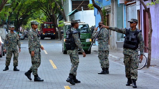Fünf Soldaten patrouillieren in einer Strasse von Malé Fünf Soldaten patrouillieren in einer Strasse von Malé