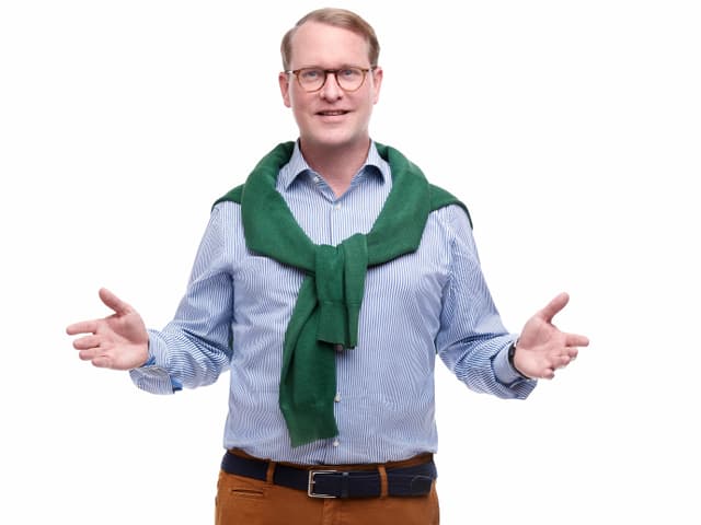 Hanspeter Vochezer im Streifenhemd, Pullover über der Schulter und braun-roter Hose Hanspeter Vochezer im Streifenhemd, Pullover über der Schulter und braun-roter Hose
