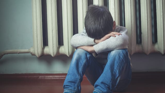 Ein Junge sitzt zusammengekauert am Boden. Ein Junge sitzt zusammengekauert am Boden.