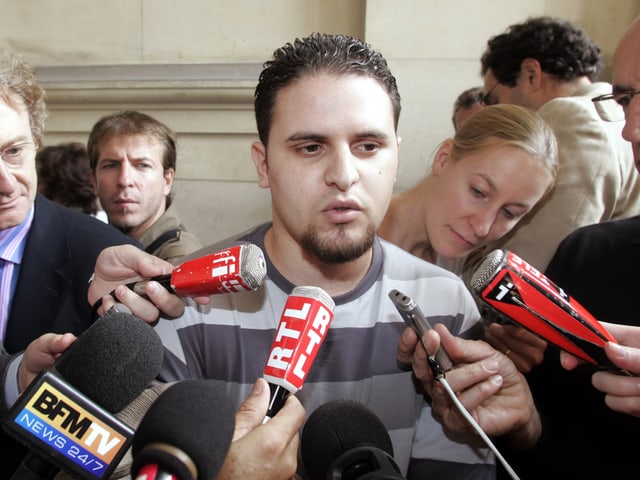 Mourad Benchellali, umringt von Mikrofonen, gibt Journalisten Interviews. Mourad Benchellali, umringt von Mikrofonen, gibt Journalisten Interviews.