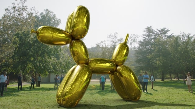 Ein grosser Ballonhund steht mitten auf einer Wiese, umgeben von Menschen, die Handys halten. Ein grosser Ballonhund steht mitten auf einer Wiese, umgeben von Menschen, die Handys halten.