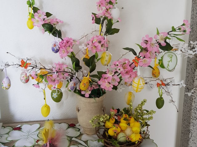 Osterbaum mit Lila Blüten und gelben Eiern.