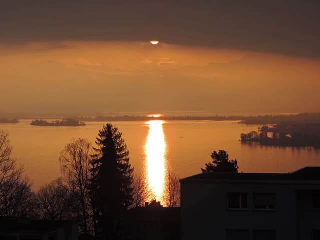 Blick über den Zürichsee Richtung Speer mit halbwegs vom Nebel abgedeckter Sonne.