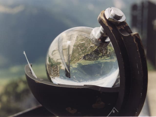 Eine Glaskugel ist in einem Gestell eingespannt. Eine Glaskugel ist in einem Gestell eingespannt.
