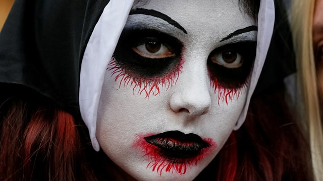 Nahaufnahme einer Person mit weiss geschminktem Gesicht und schwarzen Augen und Mund Nahaufnahme einer Person mit weiss geschminktem Gesicht und schwarzen Augen und Mund