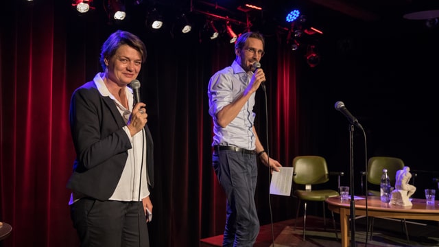 Anne Baecher und Yves Bossart je mit einem Mikro in der Hand auf der Bühne. Anne Baecher und Yves Bossart je mit einem Mikro in der Hand auf der Bühne.