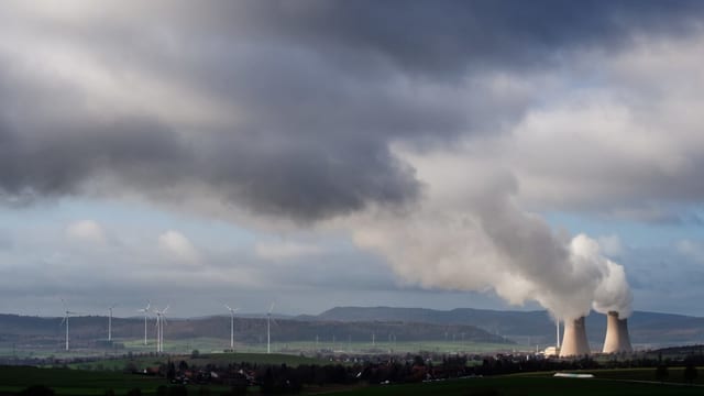 Symbolbild: Ein AKW mit zwei Kühltürmen aus der Ferne, daneben ein Windpark. Symbolbild: Ein AKW mit zwei Kühltürmen aus der Ferne, daneben ein Windpark.