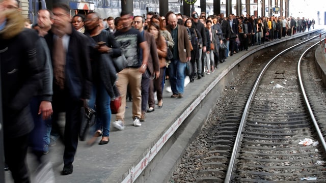 Vielen Menschen laufen auf einem Bahnperron ohne Zug Vielen Menschen laufen auf einem Bahnperron ohne Zug