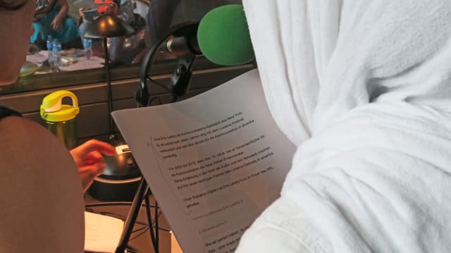 Eine junge Frau mit Kopftuch liest ihr Manuskript in einer Live-Radiosendung. Eine junge Frau mit Kopftuch liest ihr Manuskript in einer Live-Radiosendung.