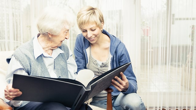 Eine junge Frau und eine ältere Dame schauen ein Buch an.