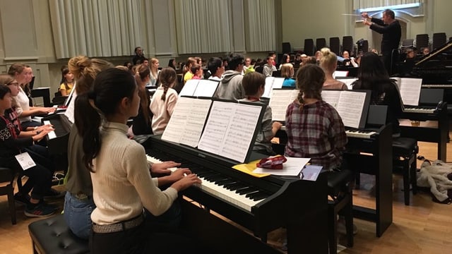 Viele Kinder sitzen an Klavier Viele Kinder sitzen an Klavier
