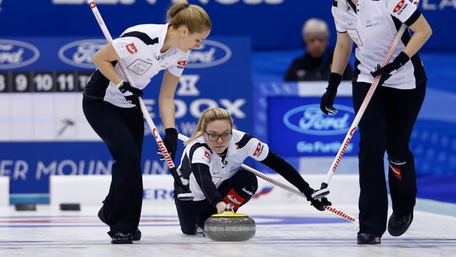 Eine Frau schiebt ein Curlingstein über das Eis. Eine Frau schiebt ein Curlingstein über das Eis.