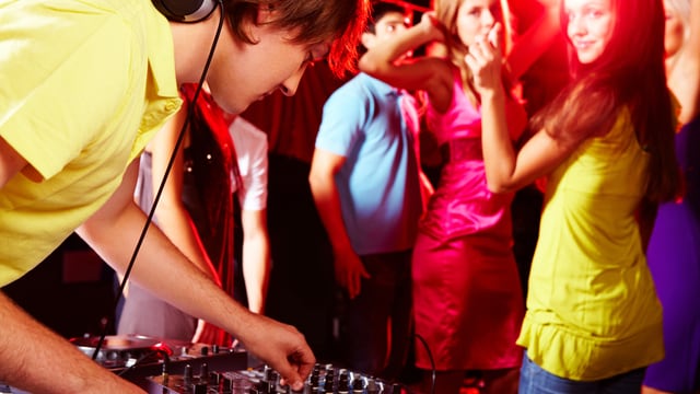 DJ mischt Musik, im Hintergrund tanzende Menschen DJ mischt Musik, im Hintergrund tanzende Menschen