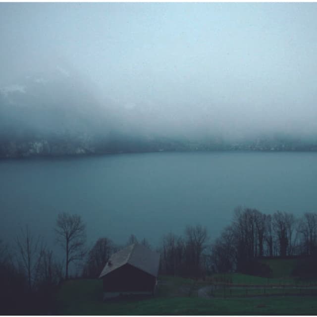 Eine mächtige Regenwolke hängt über einem See, das andere Ufer erkennt man nur noch knapp. Eine mächtige Regenwolke hängt über einem See, das andere Ufer erkennt man nur noch knapp.
