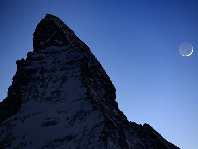 Das Mattherhorn der Nachthimmel leuchtet hell- bis dunkelblau, die Mondsichel ist zu erkennen. Das Mattherhorn der Nachthimmel leuchtet hell- bis dunkelblau, die Mondsichel ist zu erkennen.