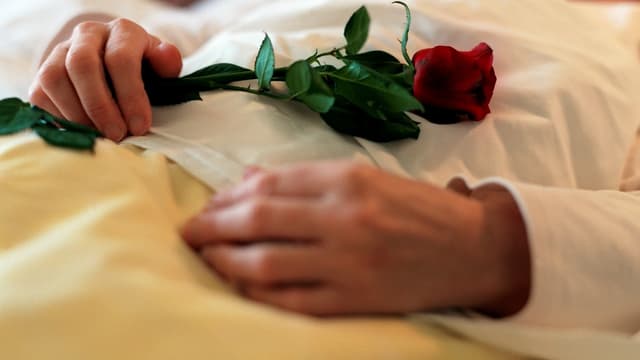 Hände einer Verstorbenen halten eine Rose. Hände einer Verstorbenen halten eine Rose.