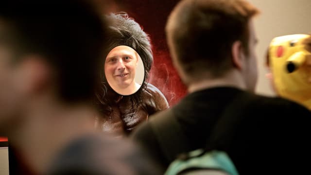 Hinter einer Pappfigur schaut ein Mann verschmitzt.