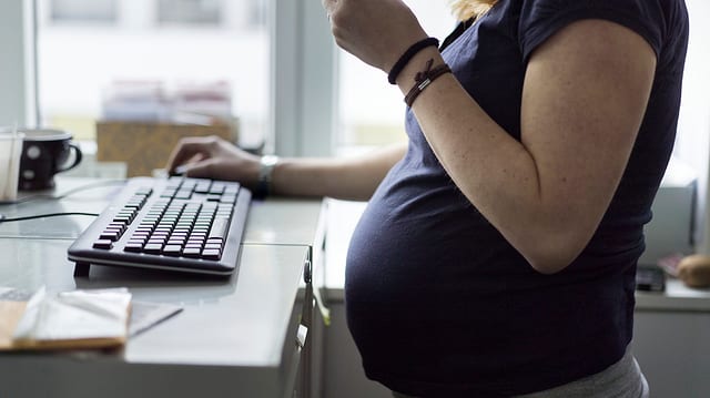 Eine schwangere Frau in einem Büro.