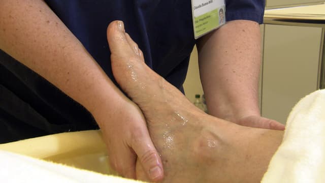 Eine Fachperson reibt den Fuss einer Patientin mit Öl ein. Eine Fachperson reibt den Fuss einer Patientin mit Öl ein.