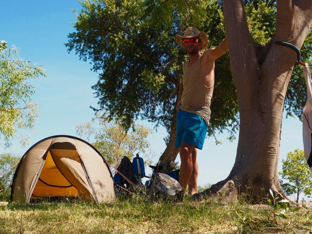Ein Mann steht neben seinem Zelt.