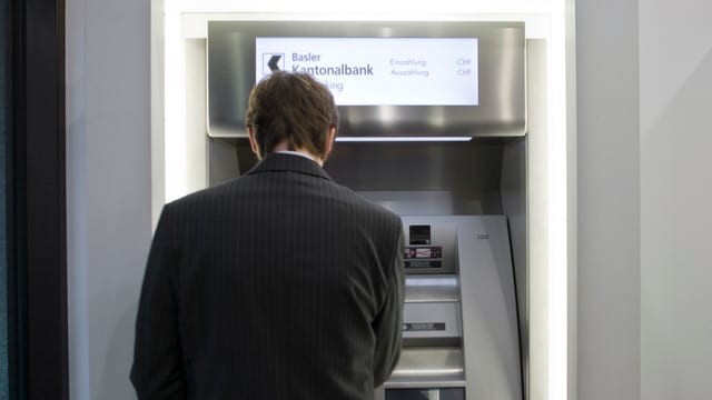 Mann steht vor Bancomat. Mann steht vor Bancomat.