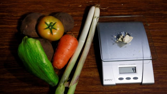 Eine Peperoni, eine dicke Karotte, eine Tomate, zwei Lauchstangen und drei grosse Kartoffeln neben einer Waage mit Cocapaste. Eine Peperoni, eine dicke Karotte, eine Tomate, zwei Lauchstangen und drei grosse Kartoffeln neben einer Waage mit Cocapaste.