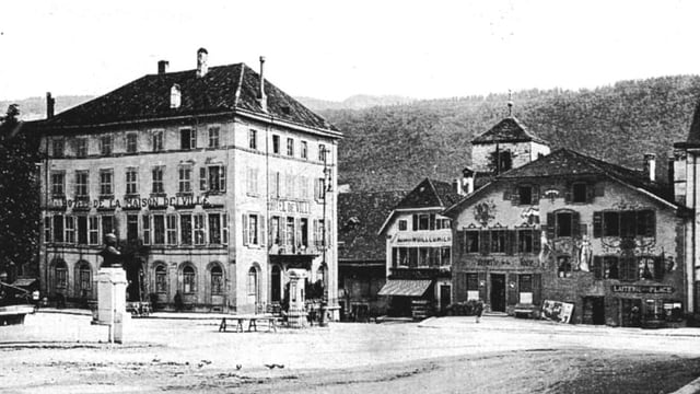 Ein grosses Haus, davor der Dorfplatz mit Brunnen, daneben ein Bauernhaus. Ein grosses Haus, davor der Dorfplatz mit Brunnen, daneben ein Bauernhaus.