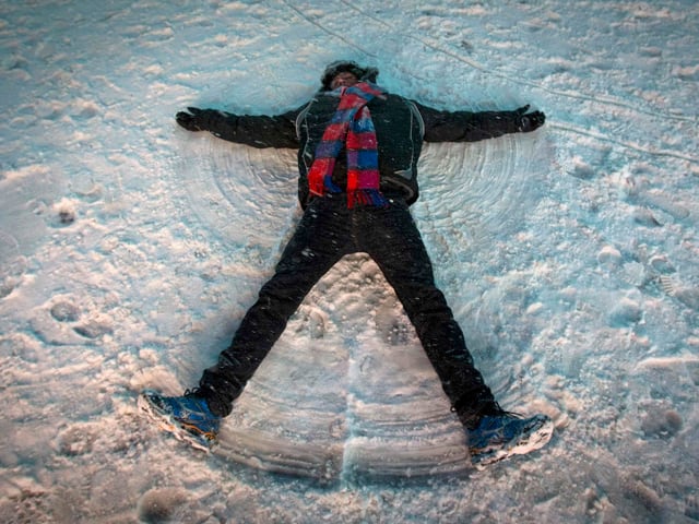 Ein Mann versucht einen Schneeengel zu machen