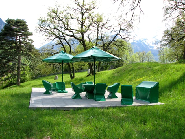 Die Installation «Eden» (2008) von Joëlle Flumet: zwei Sonnenschirme und Stühle mit grüner Schutzfolie abgedeckt Die Installation «Eden» (2008) von Joëlle Flumet: zwei Sonnenschirme und Stühle mit grüner Schutzfolie abgedeckt