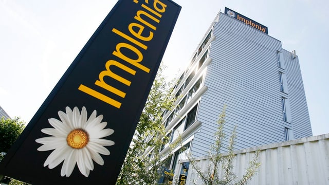 Imlplenia Hauptsitz mit Firmenlogo im Vordergrund Imlplenia Hauptsitz mit Firmenlogo im Vordergrund